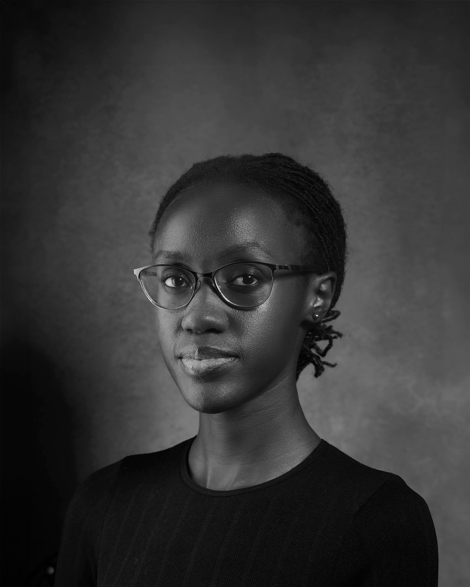 Professional black and white portrait with person wearing glasses and simple black top.
