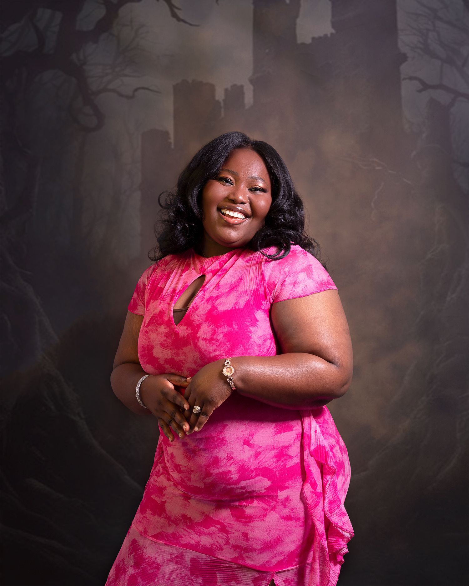 Studio portrait with person wearing vibrant pink tie-dye dress against dark background.