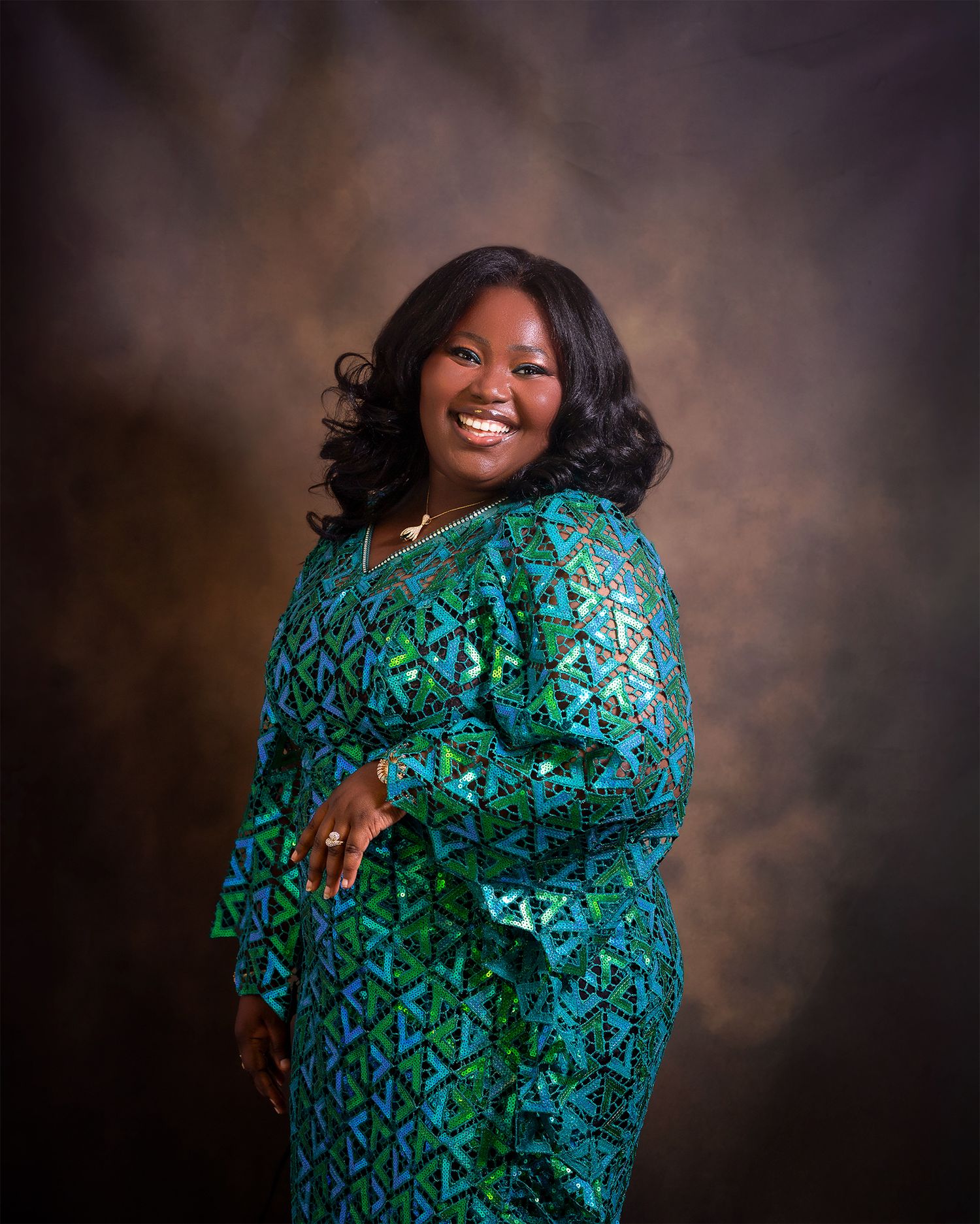 Portrait of someone wearing emerald green patterned dress in professional studio setting.