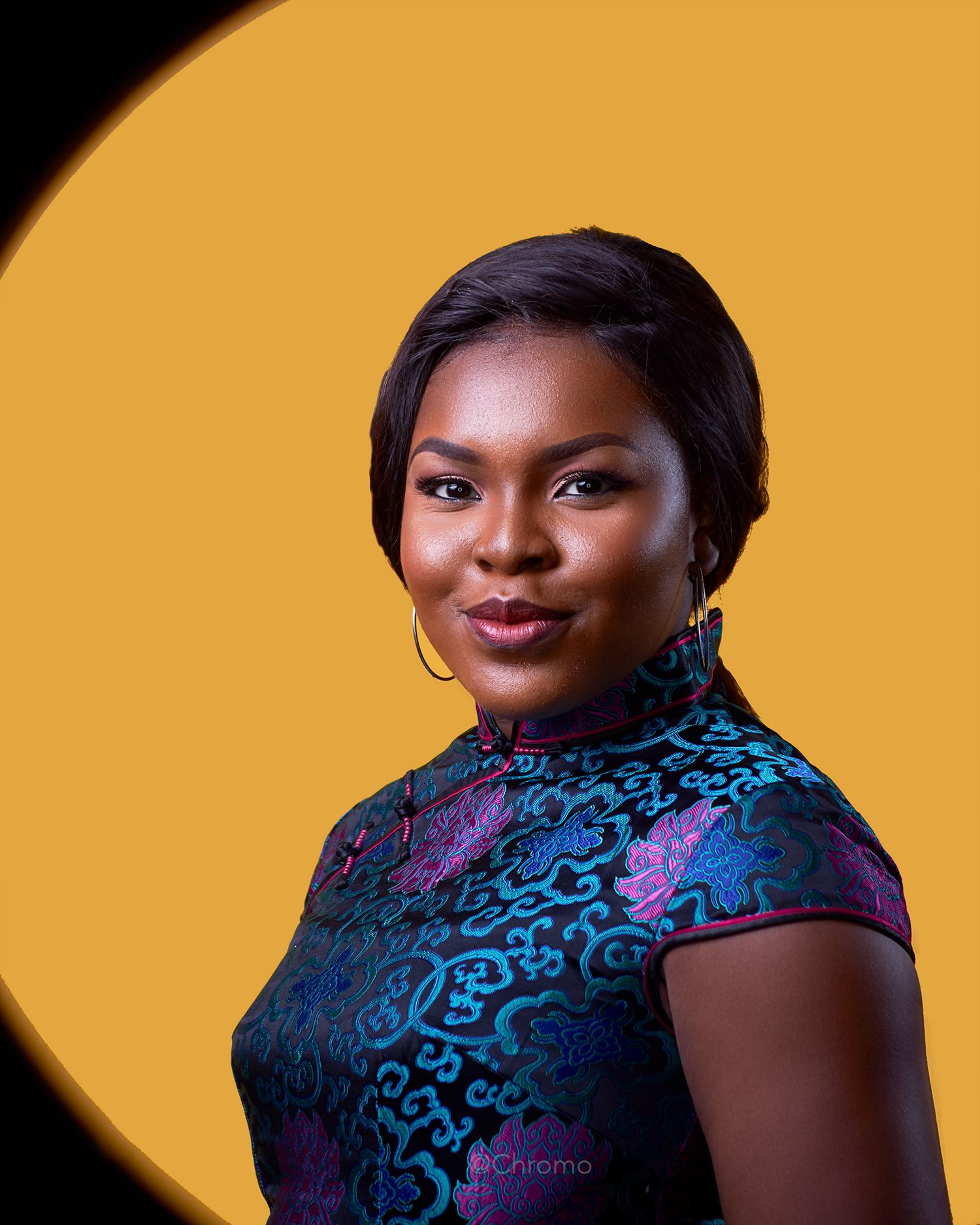 Studio portrait against orange background featuring elegant blue and purple patterned dress.