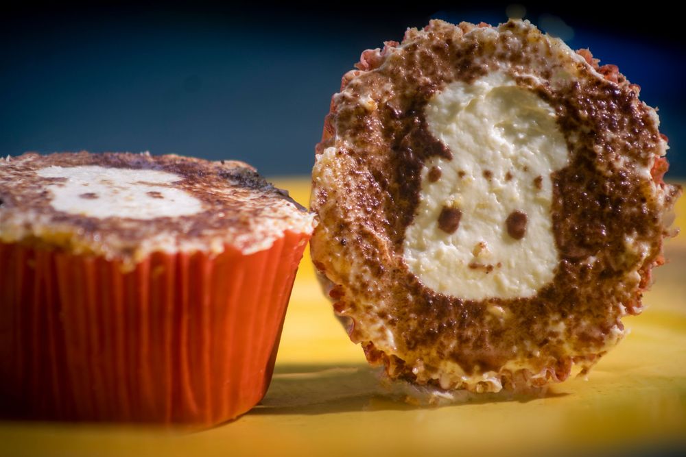 Chocolate brigadeiro truffle cut in half revealing creamy white filling in orange cupcake liner.