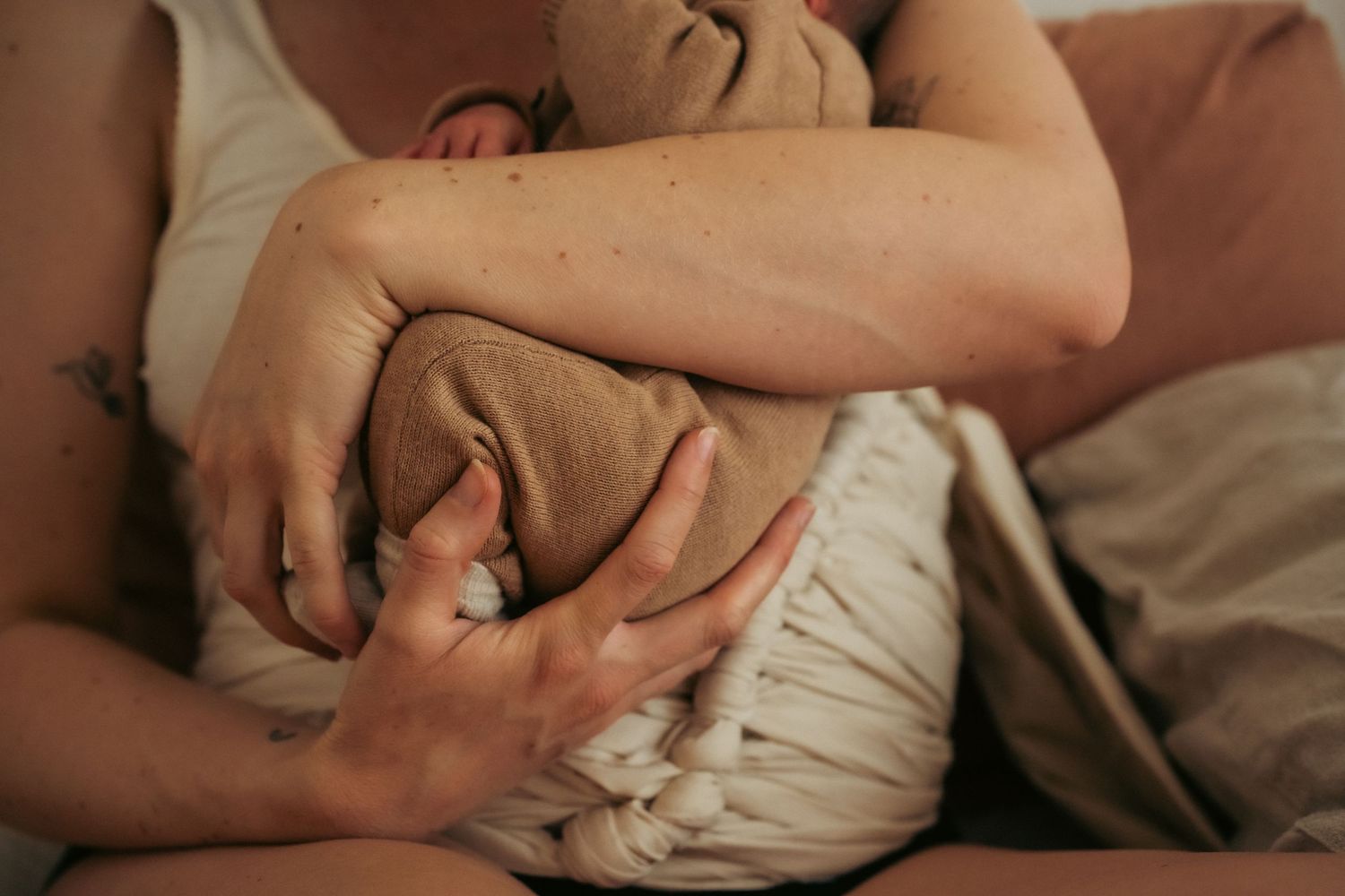 postpartum moeder met belly binding in de kraamweek houdt haar pasgeboren baby vast