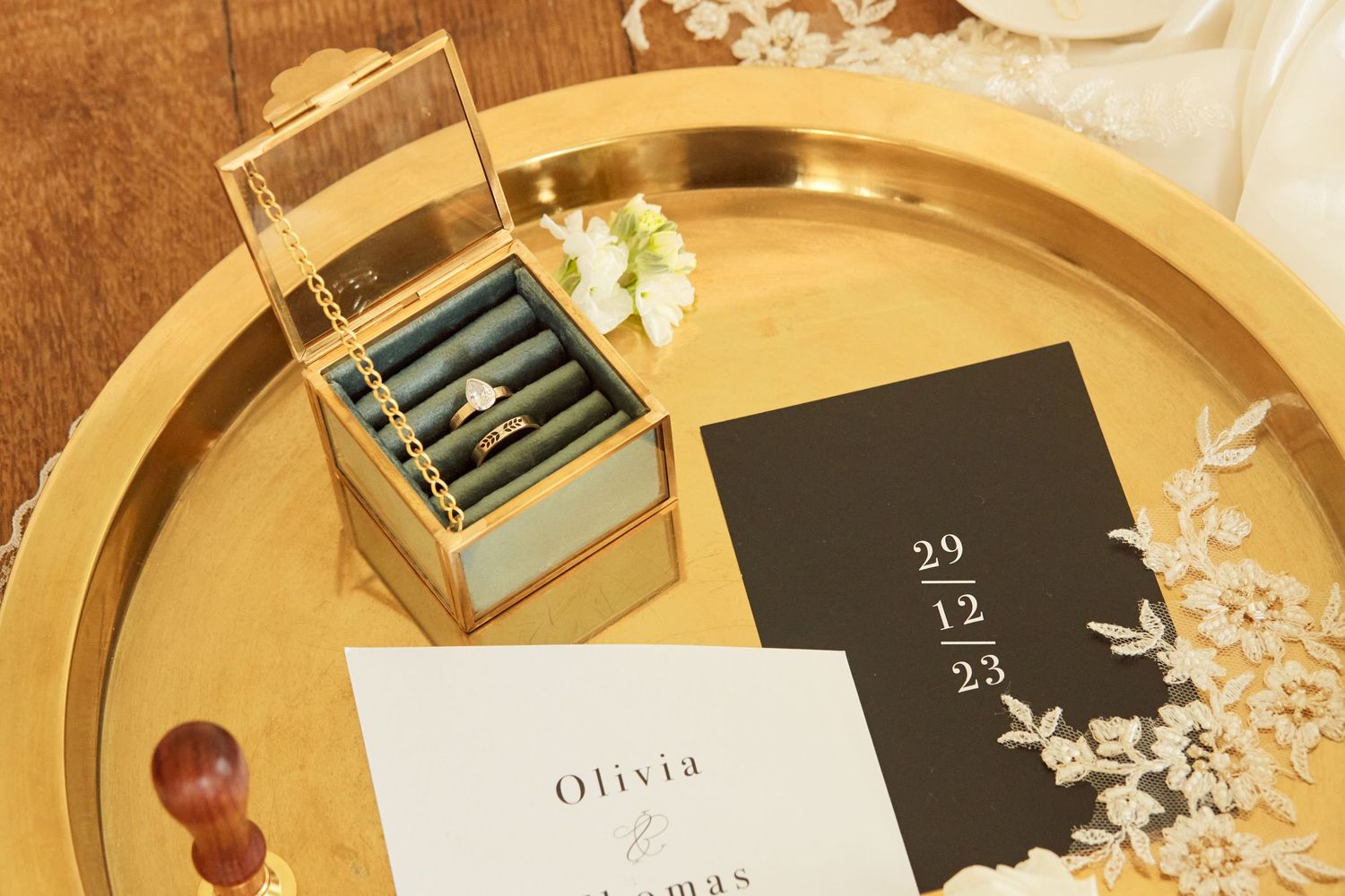 Wedding details arranged on a gold tray including cards and a small decorative box.