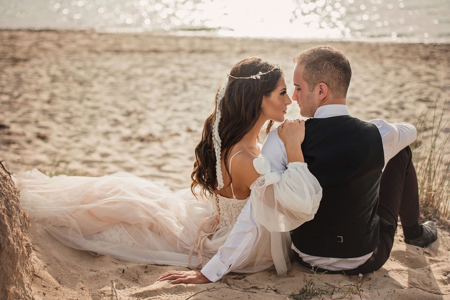 Romantic moment shared on sandy beach at sunset with flowing dress.