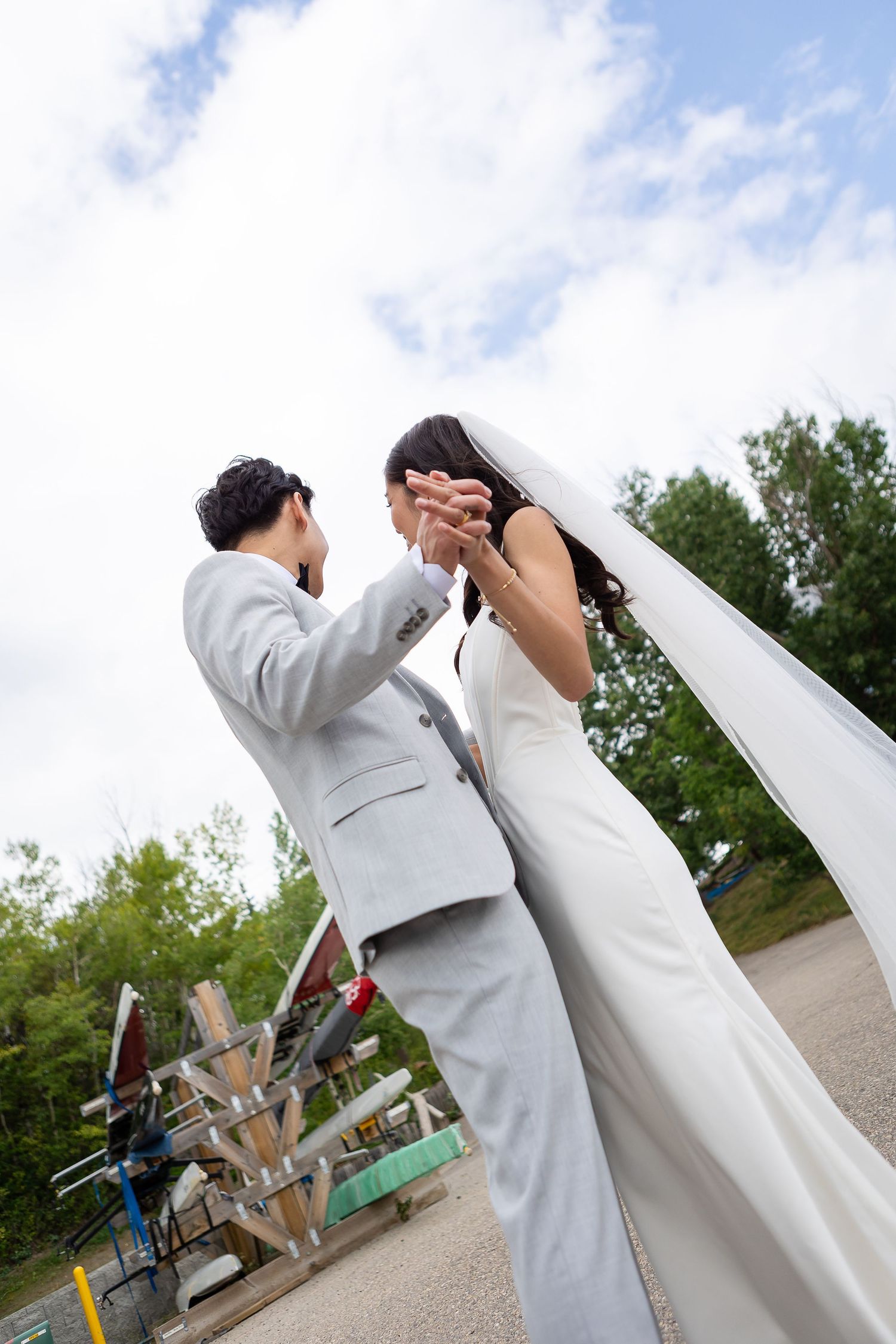 Creative low angle shot of couple in wedding attire against blue sky.
