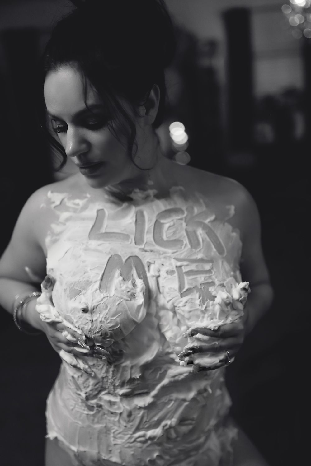 Artistic black and white photo showing torso covered in white cream or paint with text.