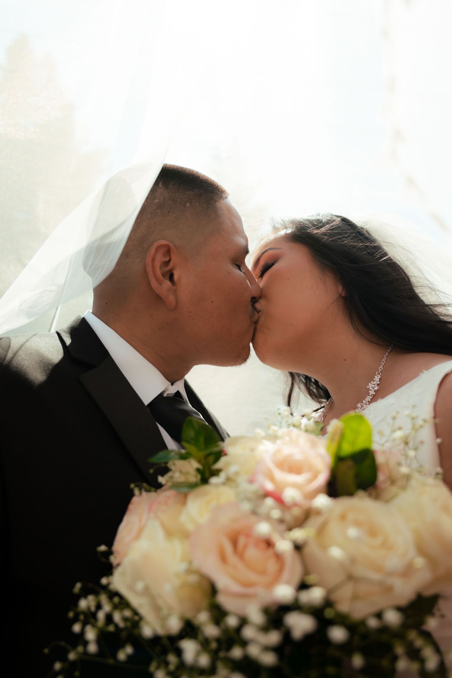 Romantic wedding moment with pink rose bouquet in foreground.