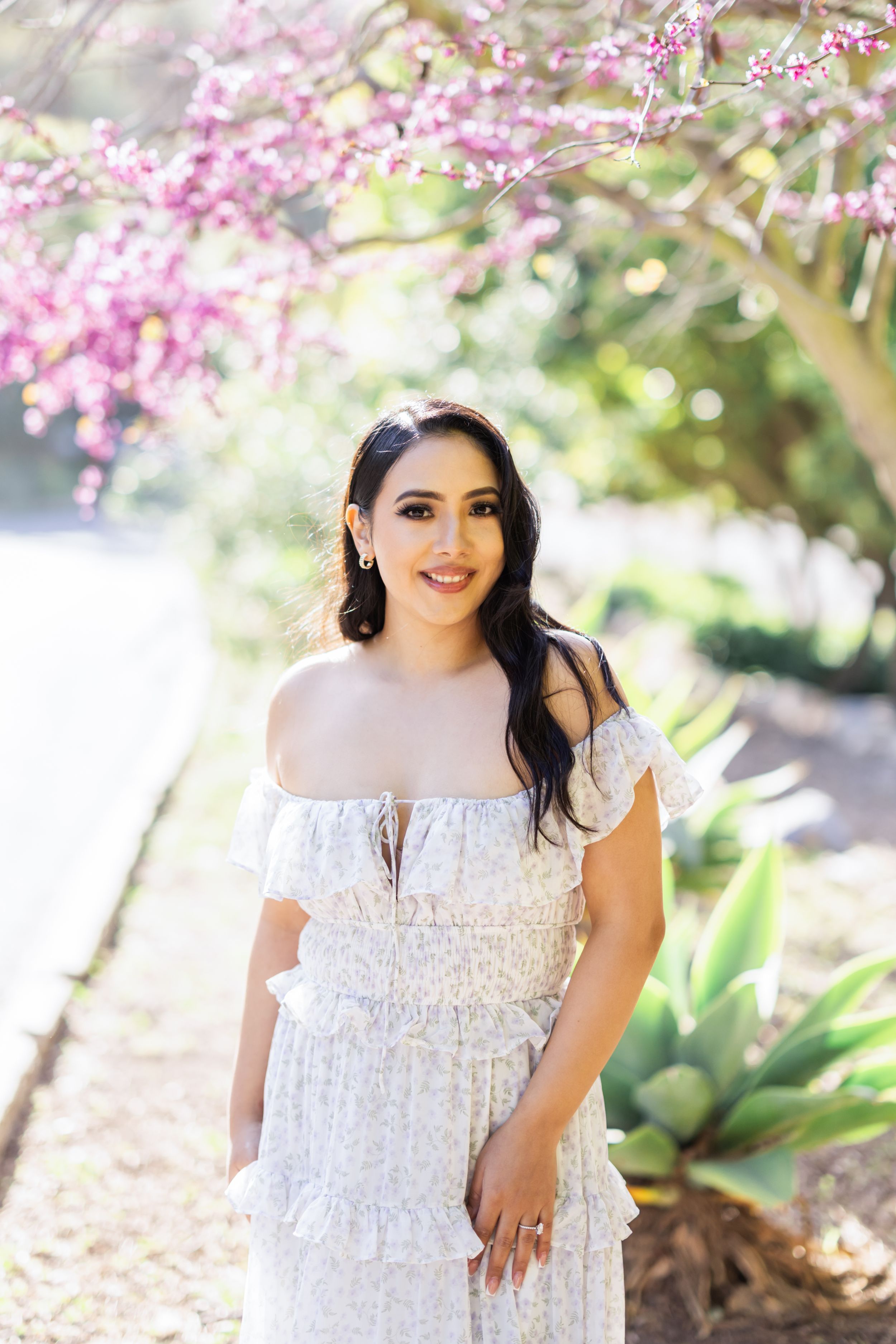 White lace dress photographed in a garden setting with pink cherry blossoms.