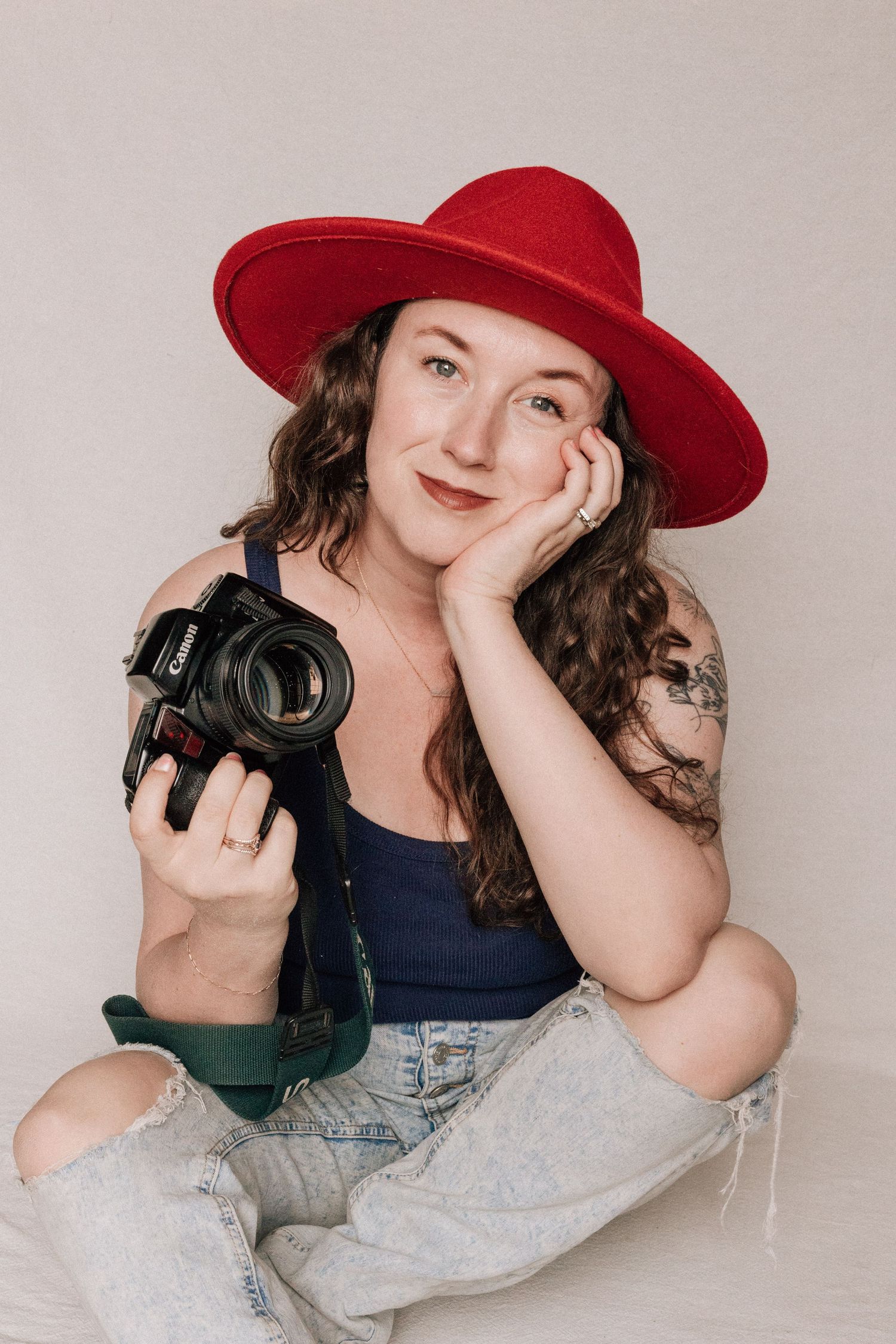 A smiling woman holds her camera. She is a professional photographer.