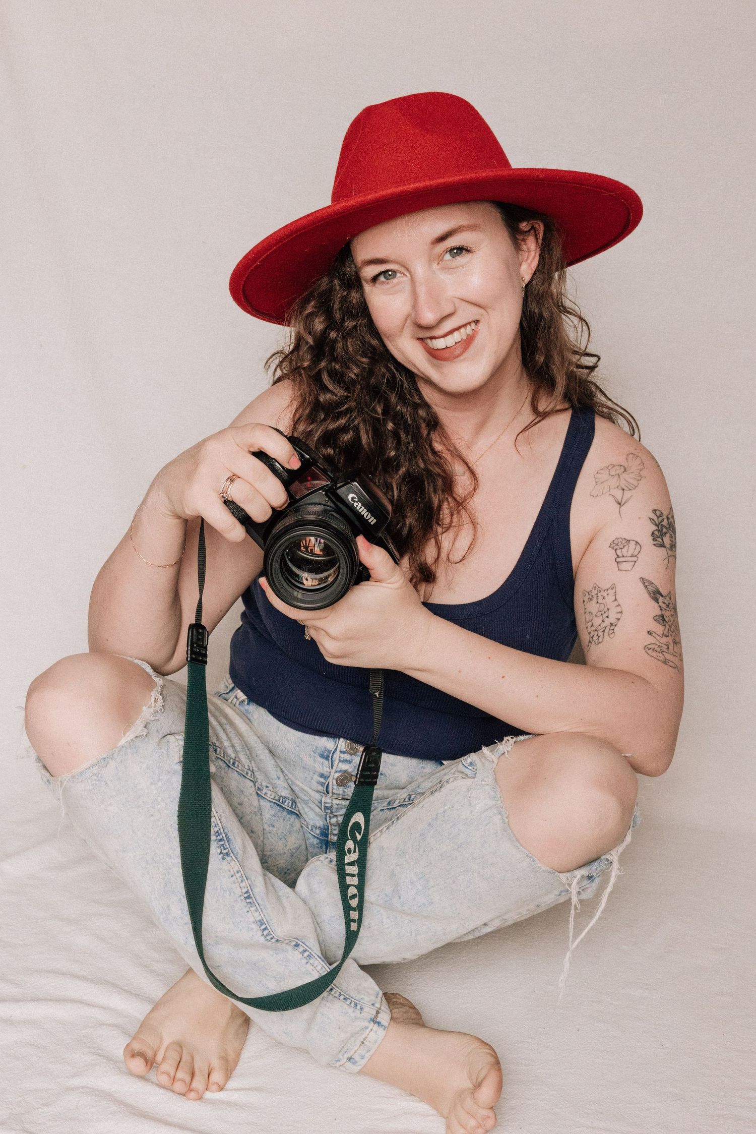 A smiling woman holds her camera. She is a professional film photographer in California and North Carolina.