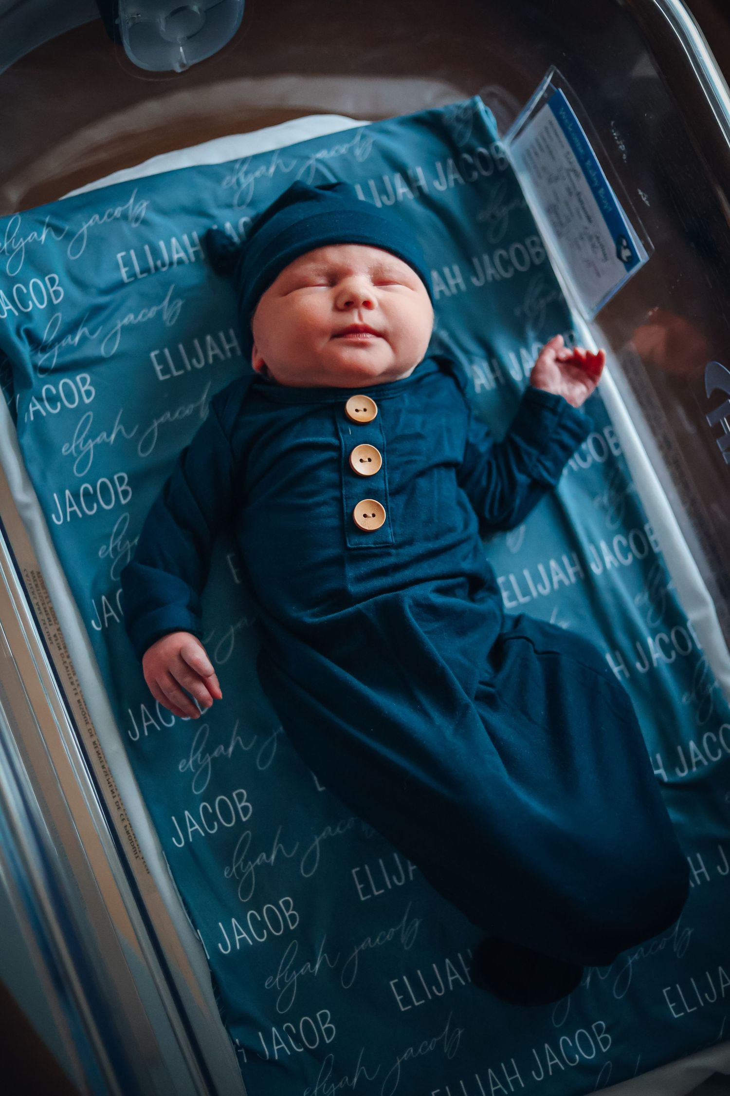 Baby wearing navy blue outfit lies on matching blue blanket with text overlay. Fresh 48 photography