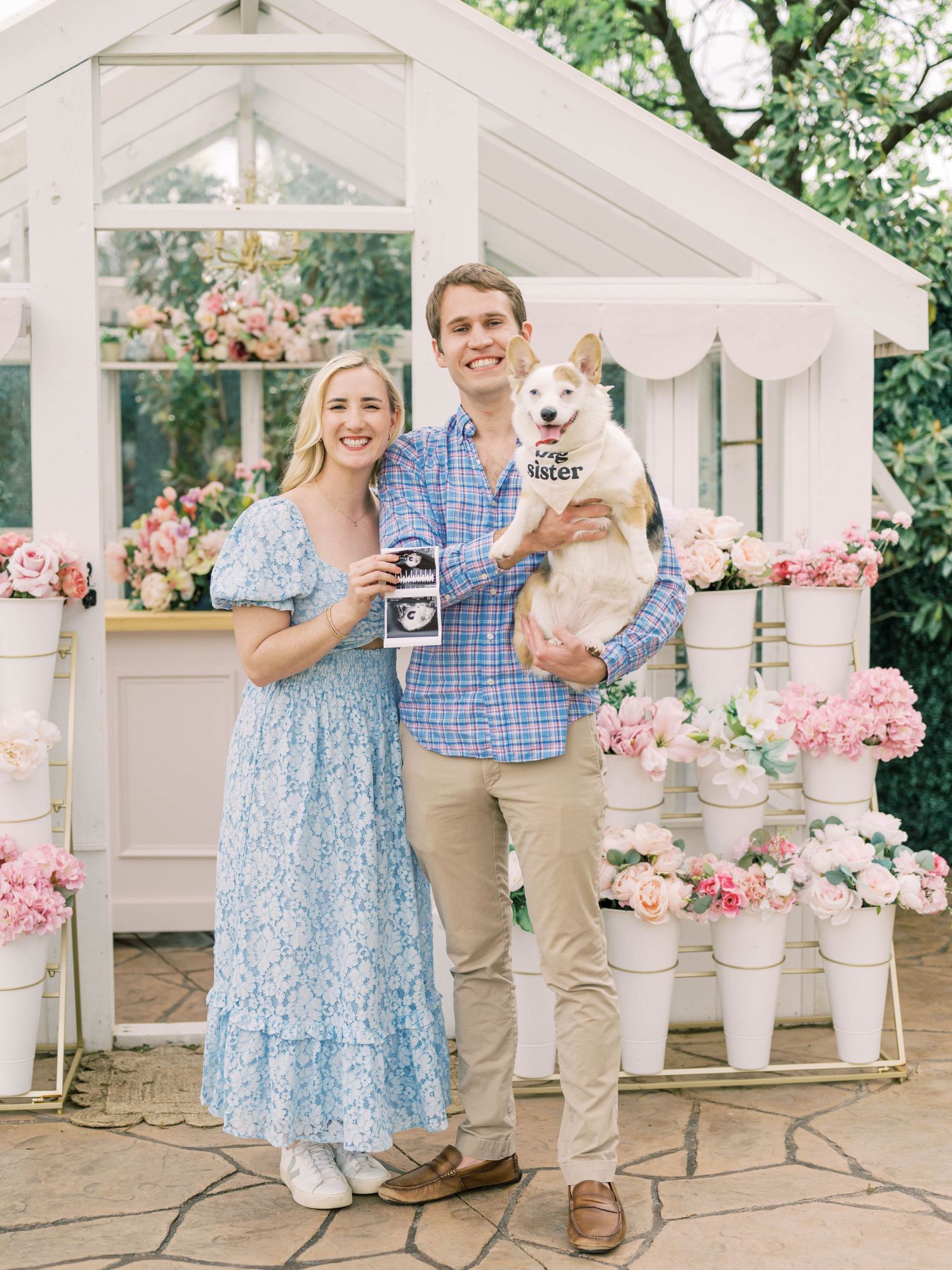 greenhouse pregnancy announcement photo of a couple and their corgi