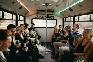 People gather in a crowded party bus or train car with colorful lighting and drinks in hand.