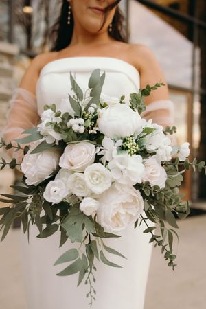 White bridal bouquet with roses, eucalyptus leaves and delicate greenery creates an elegant wedding arrangement.