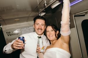 Group of friends celebrating at a party with drinks and raised hands in an indoor venue.