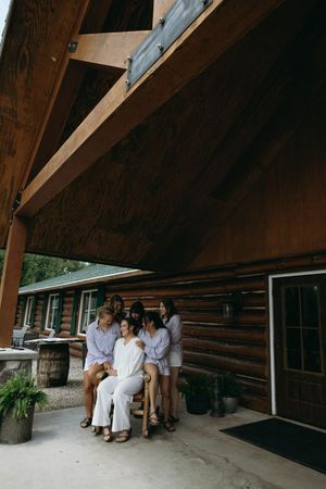 A group in matching outfits gathered on the porch of a rustic log cabin lodge.
