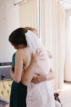 An emotional embrace between two people in a sunlit room with light-colored curtains and elegant decor.