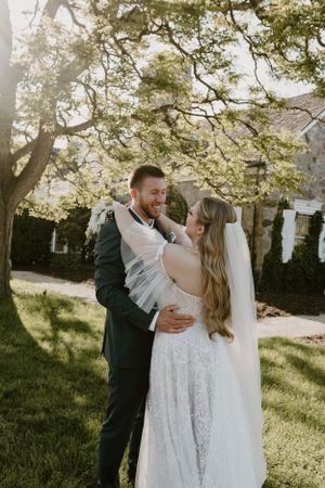 A romantic outdoor wedding portrait of a couple embracing under blooming spring trees.
