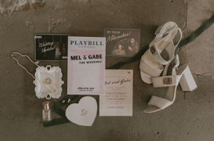 Wedding detail flat lay with playbill, shoes, and decorative elements in vintage tones.
