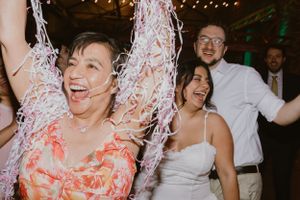 Wedding celebration showing joyful dancing with confetti and string lights in the background.