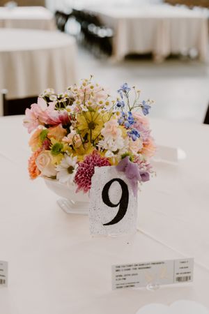 Table centerpiece with colorful wildflowers and table number 9 at a wedding reception.