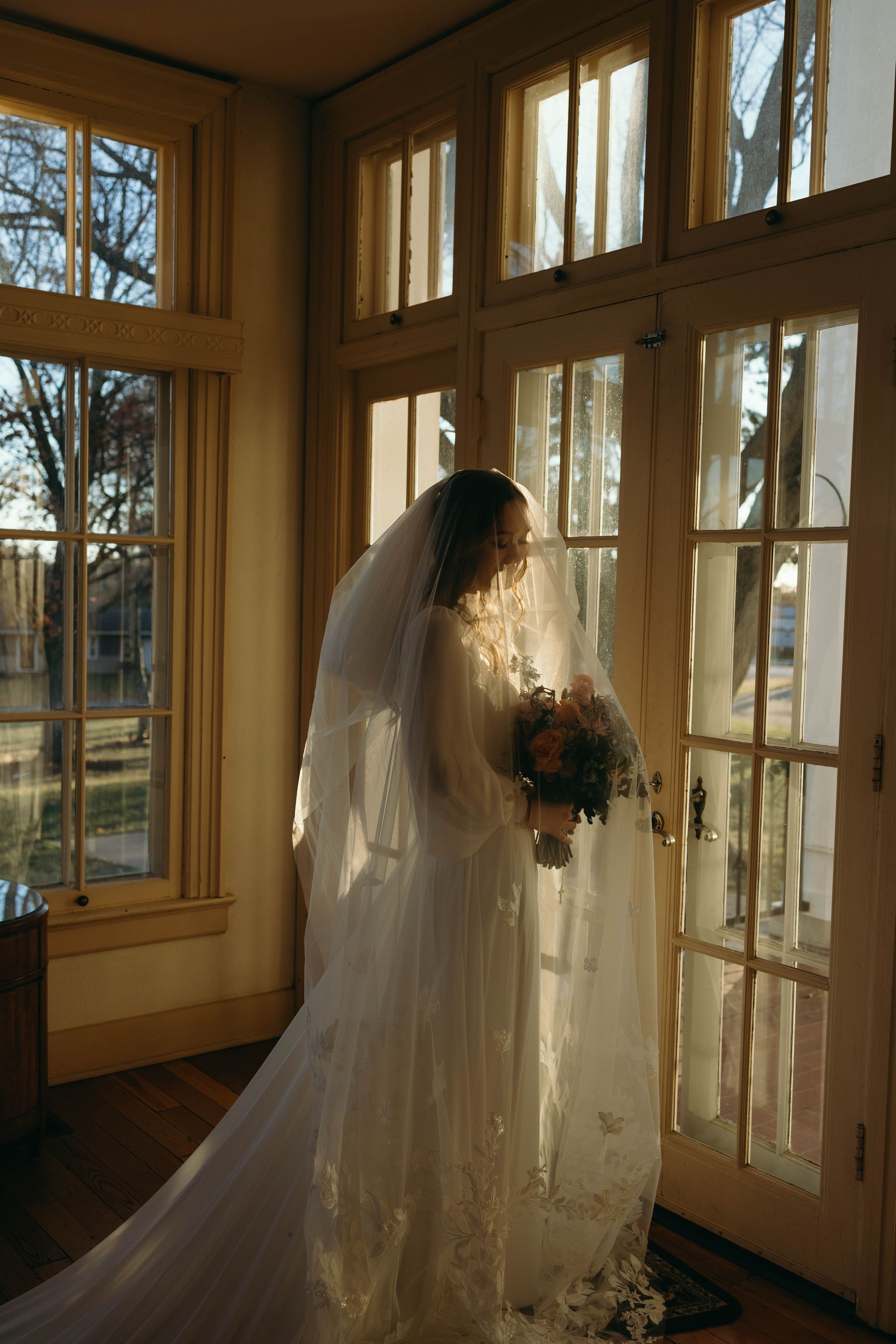 A series of connected photos shows a flowing white wedding dress and veil silhouetted against sunlit windows in a bright room.