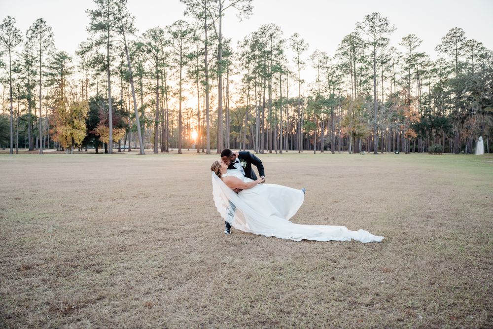 Sunset wedding photography in an open field surrounded by towering pine trees.
