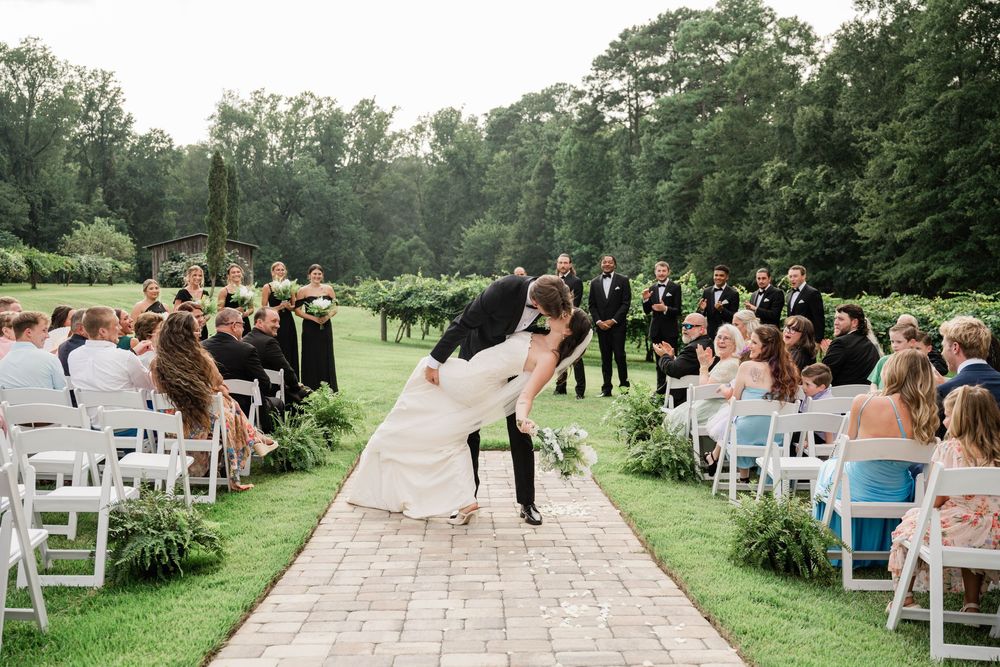 Outdoor garden wedding ceremony with white chairs and lush greenery.