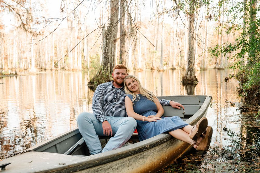 Couple relaxing together in rustic wooden boat on cypress-lined waterway.
