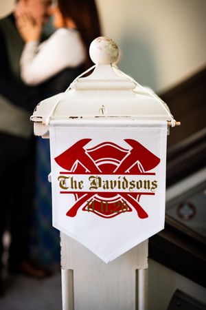 Custom firefighter wedding sign reading The Davidsons with crossed axes emblem displayed on white vintage post.