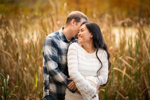 Couple sharing a romantic moment in an autumn field with golden tall grasses in the background.