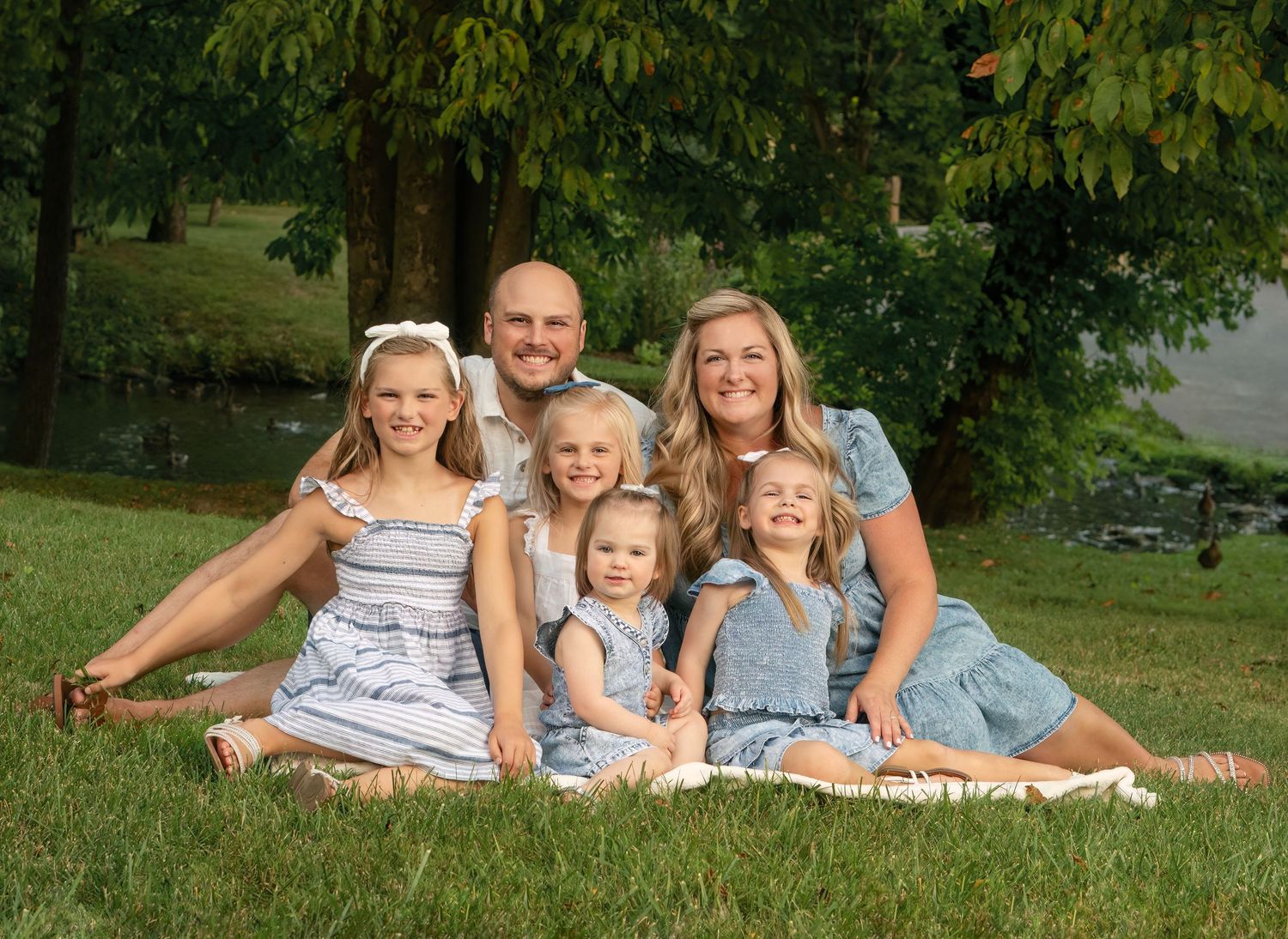 family sits together in the grass