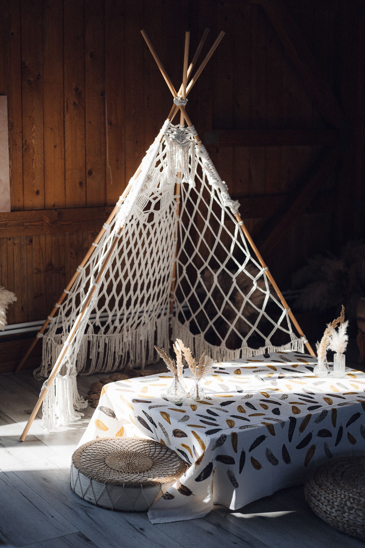 Bohemian teepee tent setup with macrame details and floor cushions in rustic interior.