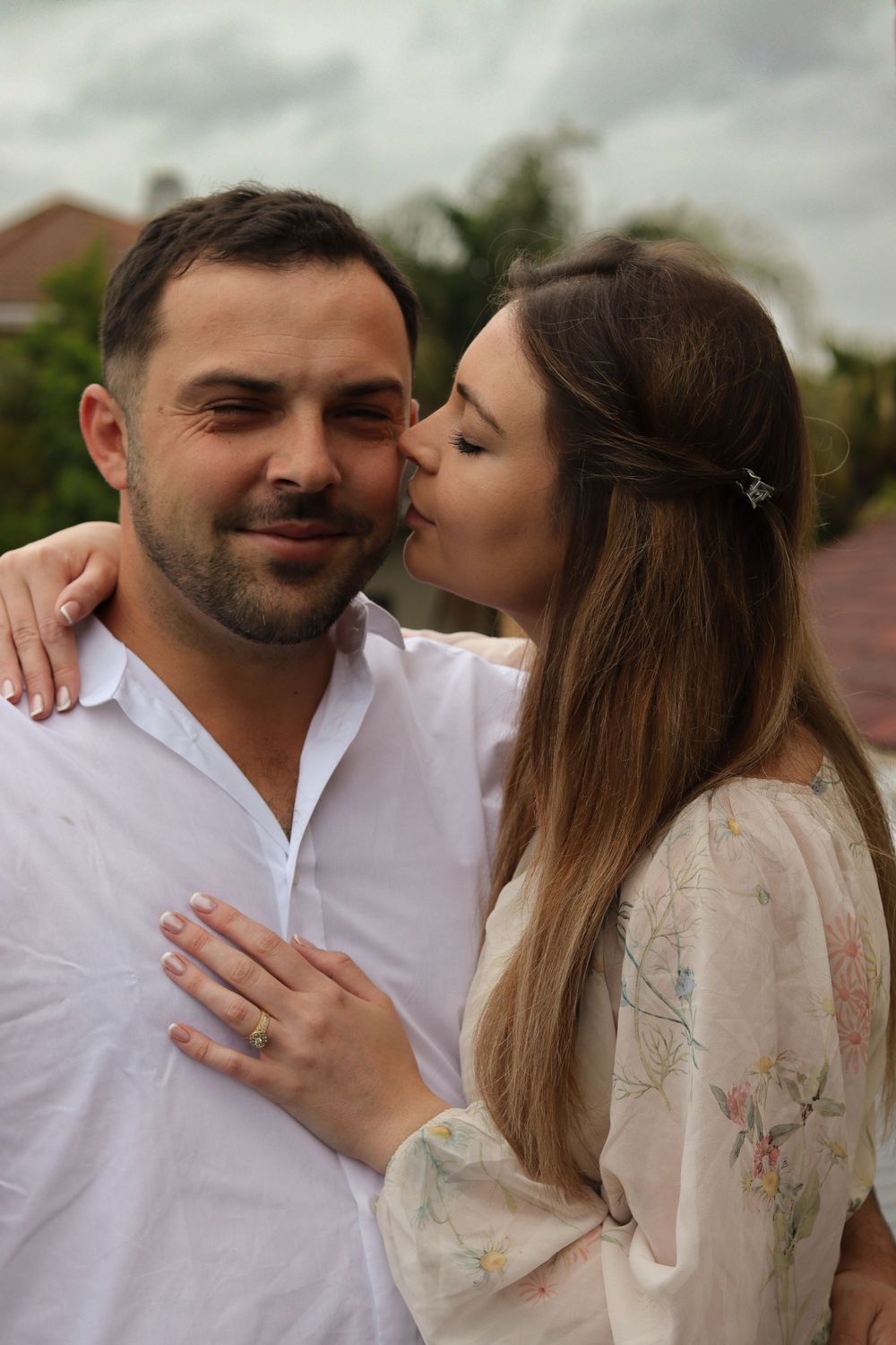 A tender moment captured between a couple outdoors on a cloudy day.