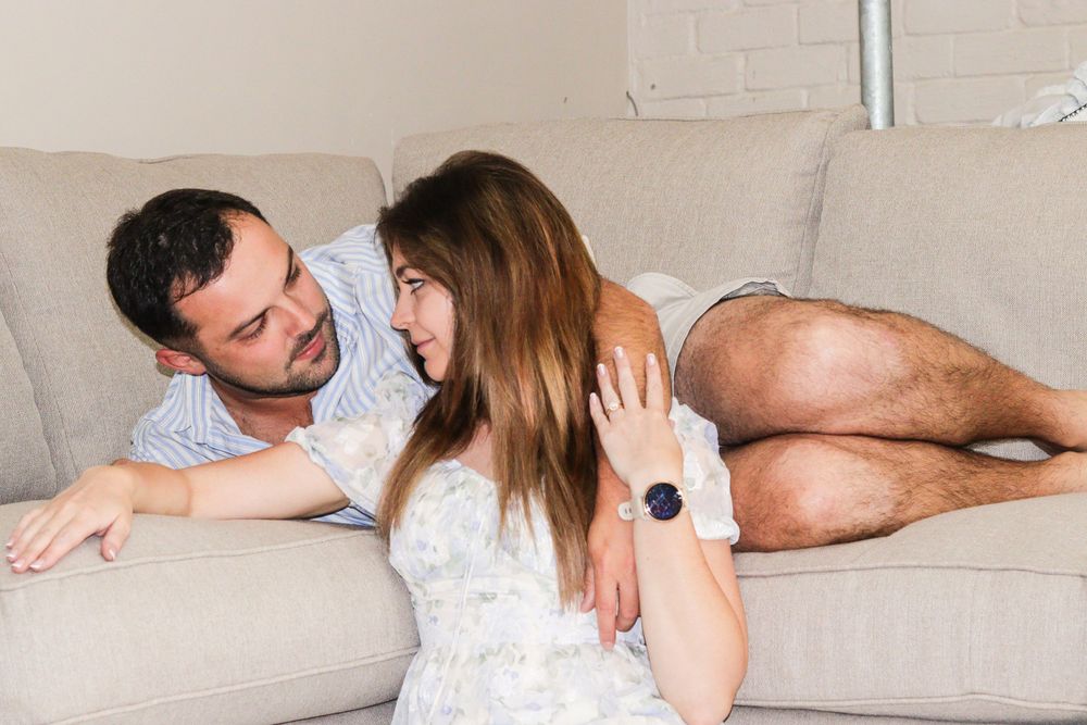 A couple sharing an intimate moment while relaxing on a light gray couch.