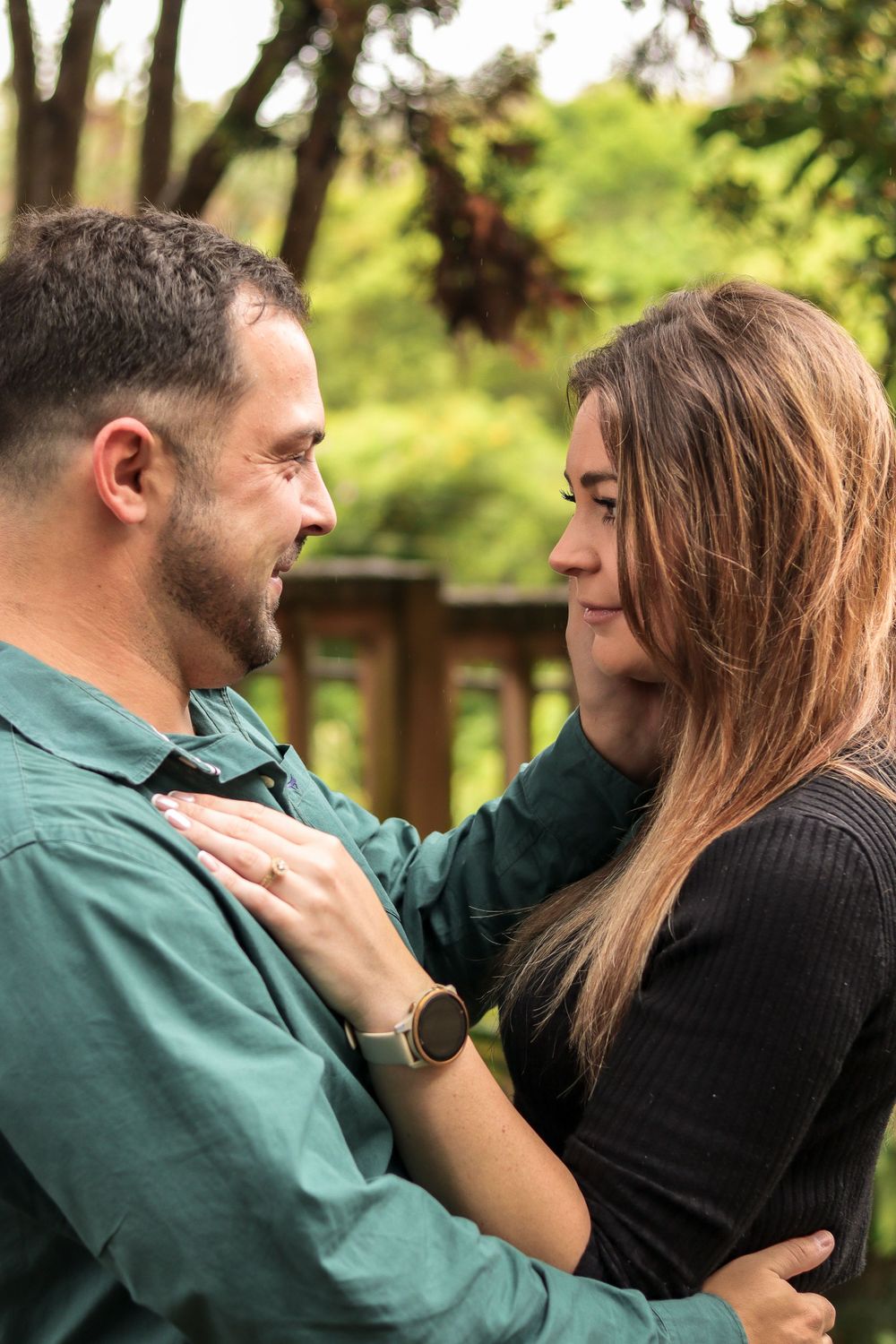 An intimate moment between a couple in casual attire standing in a garden setting.