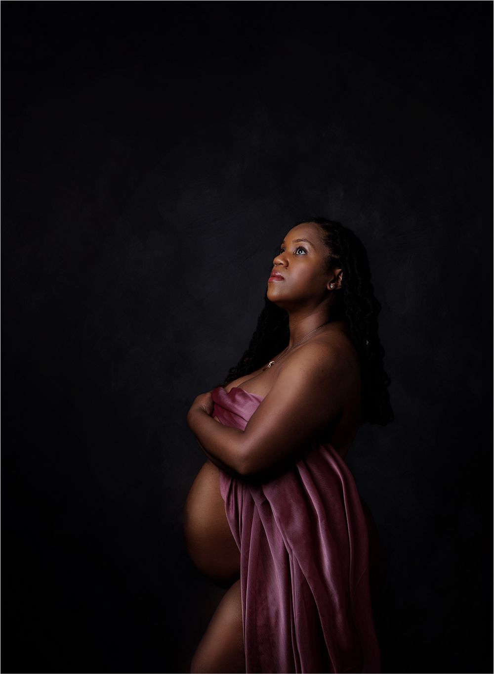 Gorgeous maternity portrait of black mom holding  pink silk with exposed belly captured by Austin Newborn Photography