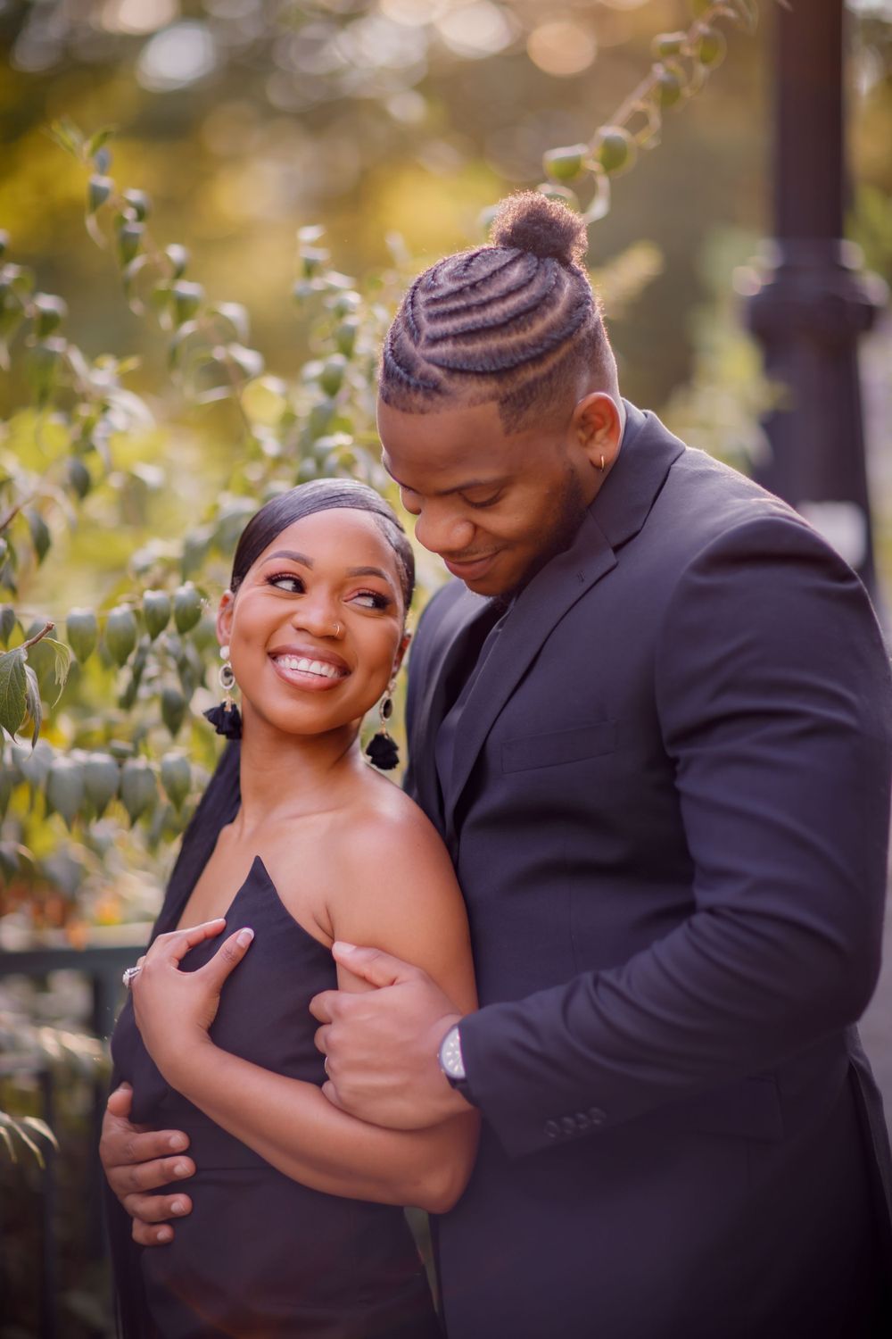 A tender moment captured between a couple in formal wear surrounded by natural greenery.