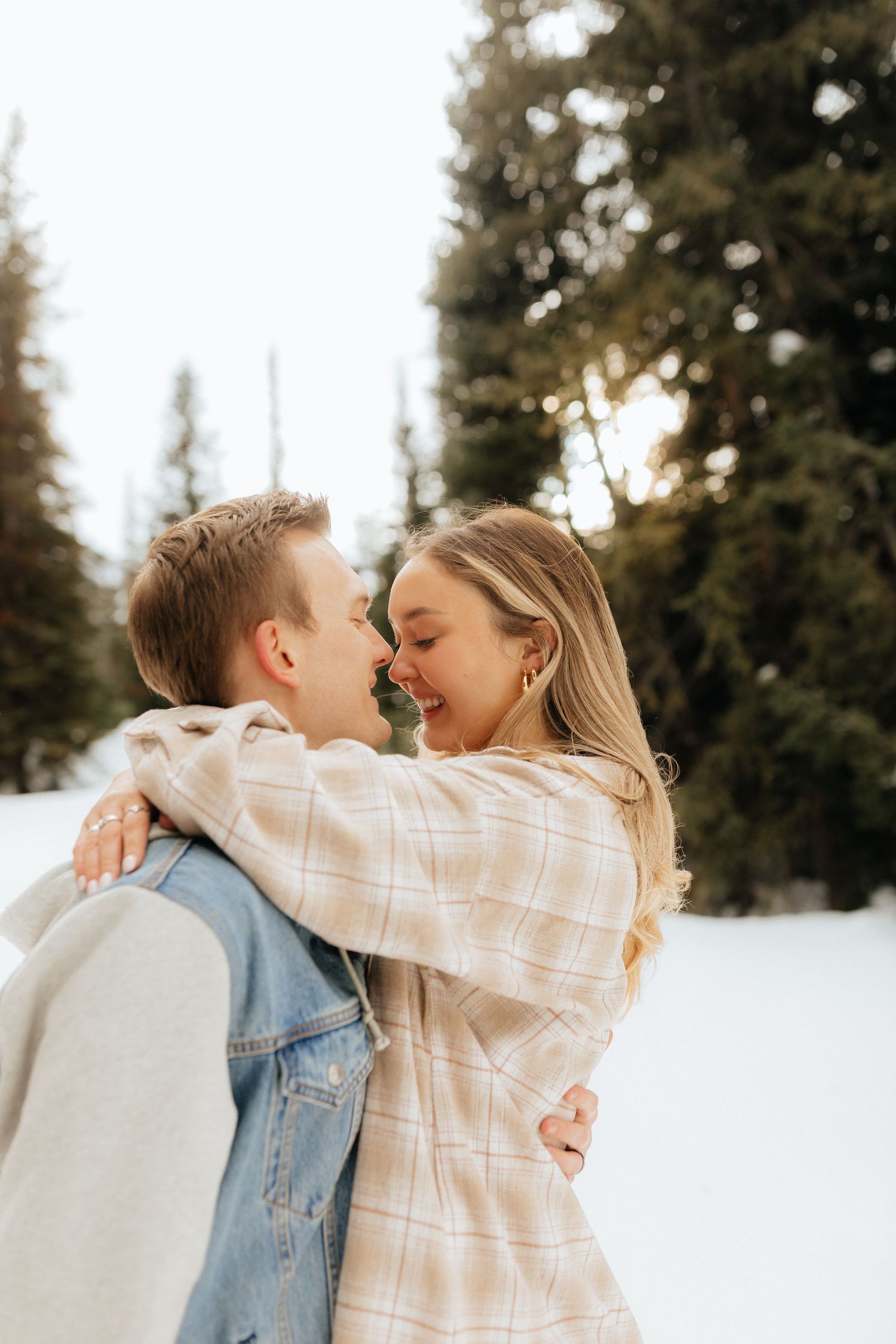 Man and woman touching noses and smiling in the woods about to kiss