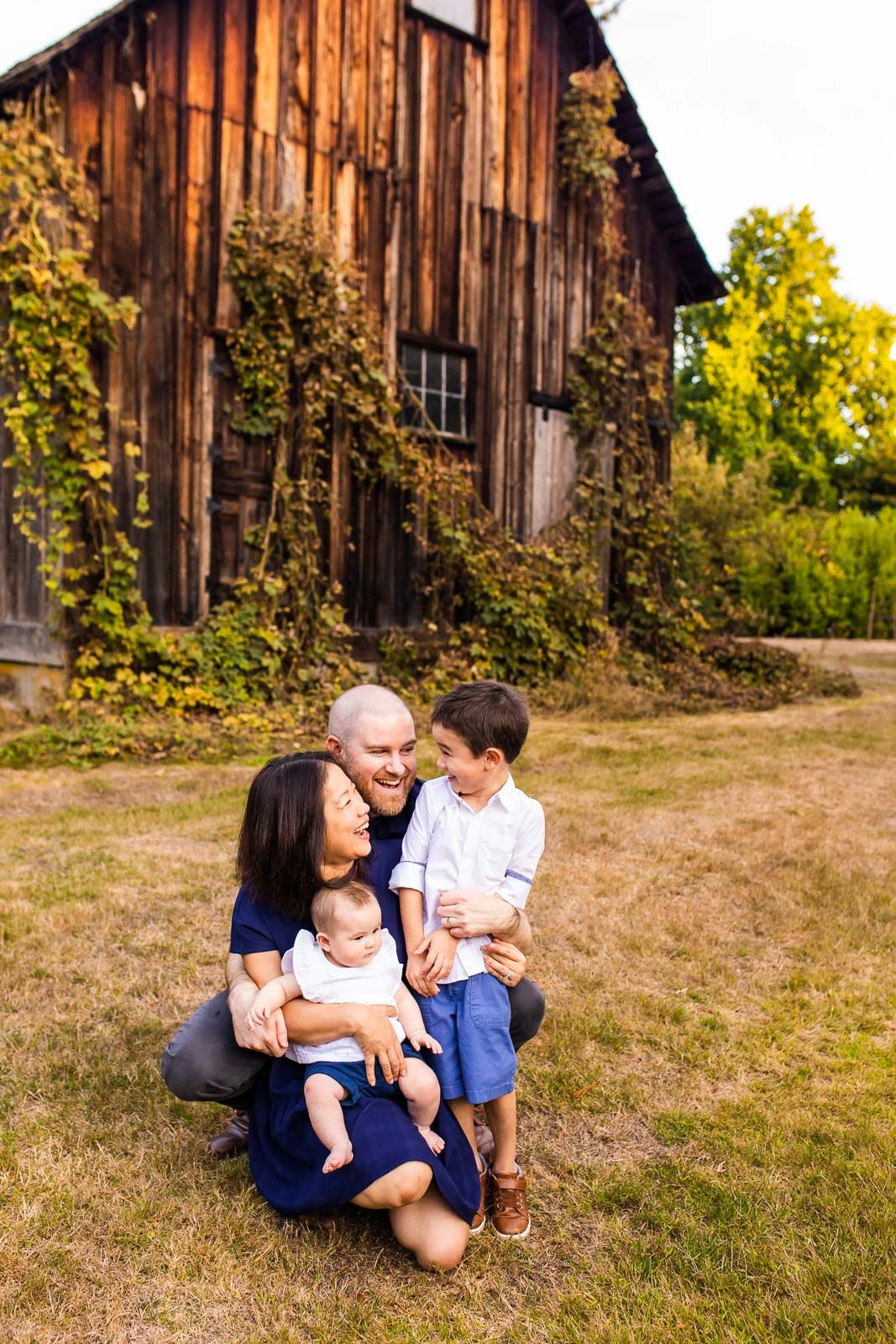 Family sitting in front of a barn laughing