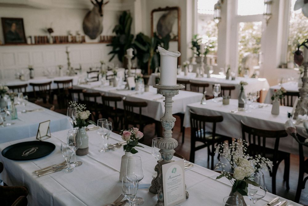 Elegant wedding reception table setup with white linens, candles and minimalist floral centerpieces.