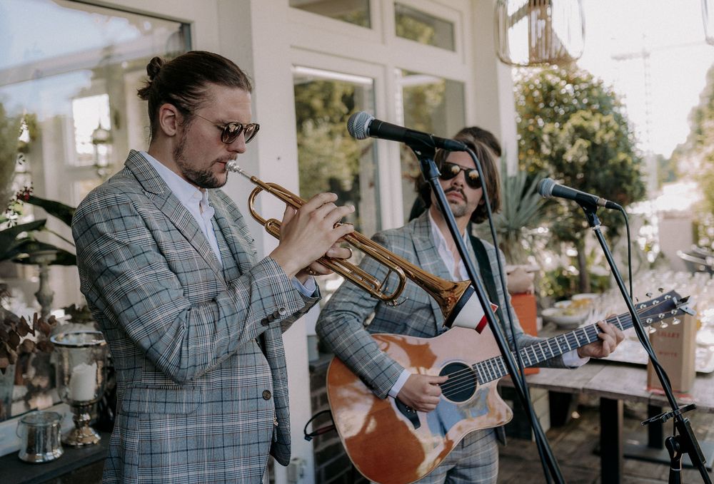 Musicians performing with trumpet and guitar at outdoor venue.