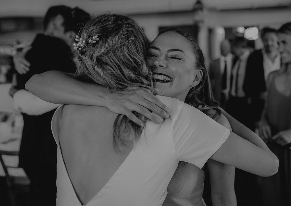 Two people sharing a joyful embrace at a celebratory event in black and white.