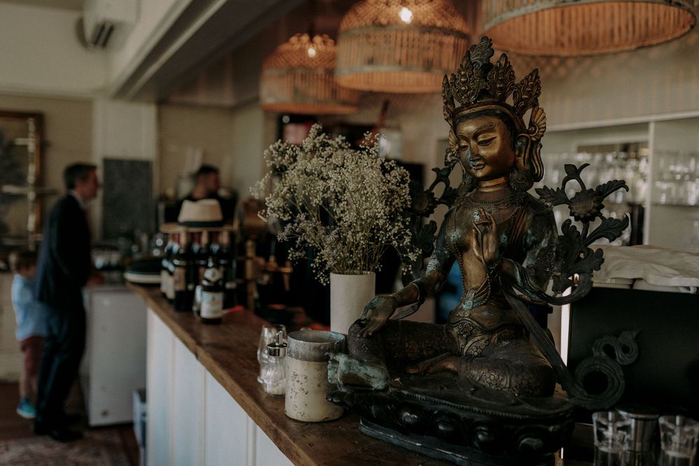 Decorative buddha statue and floral arrangements on restaurant counter.