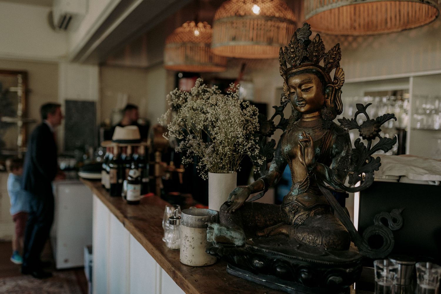 Decorative buddha statue and floral arrangements on restaurant counter.