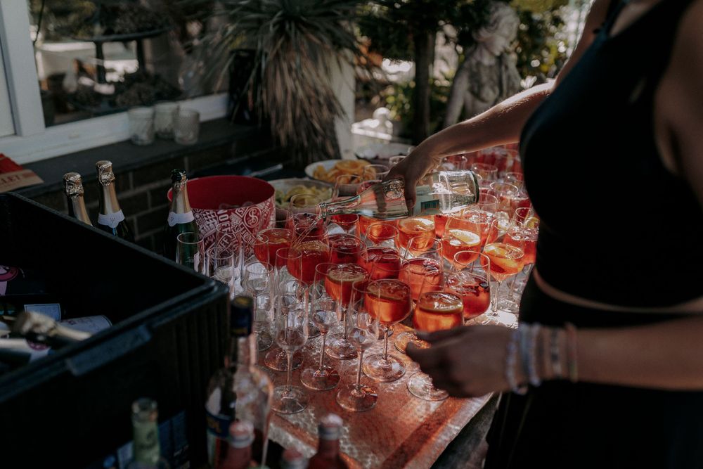 Rows of red cocktails lined up on a bar counter ready to be served.