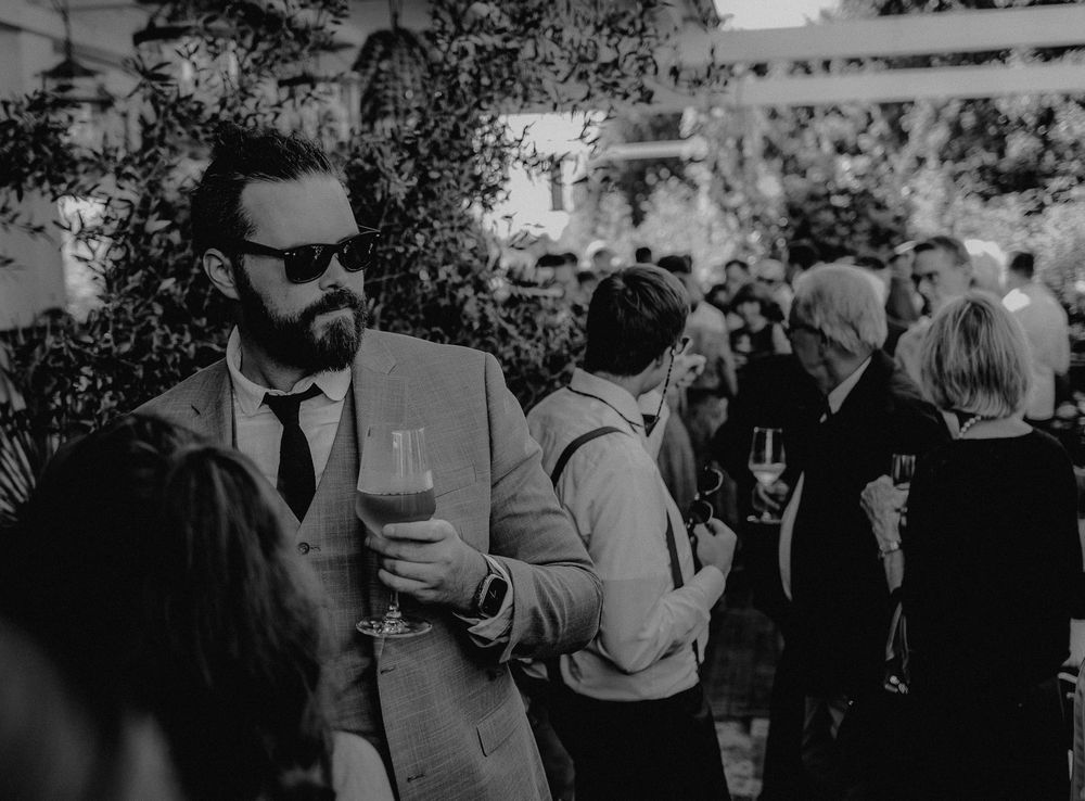 Guests mingling at an outdoor social gathering with drinks in hand.