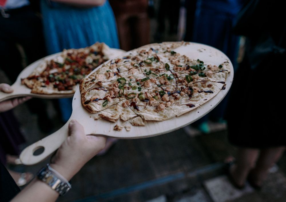 A flatbread pizza topped with herbs and toppings being served on a white plate.