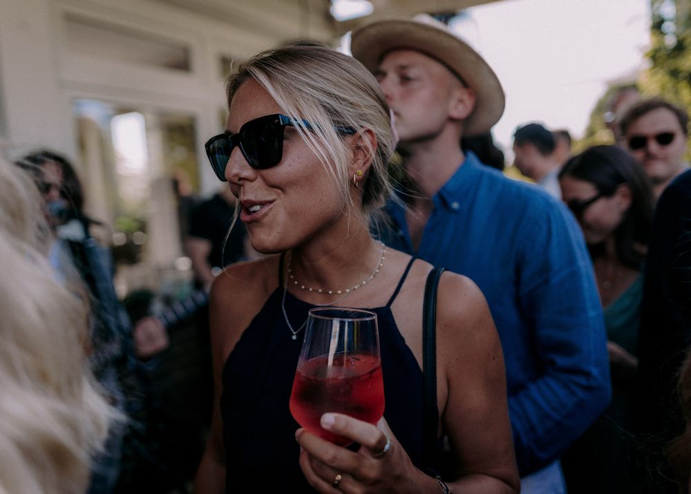 Guests enjoying drinks at an outdoor social gathering on a sunny day.