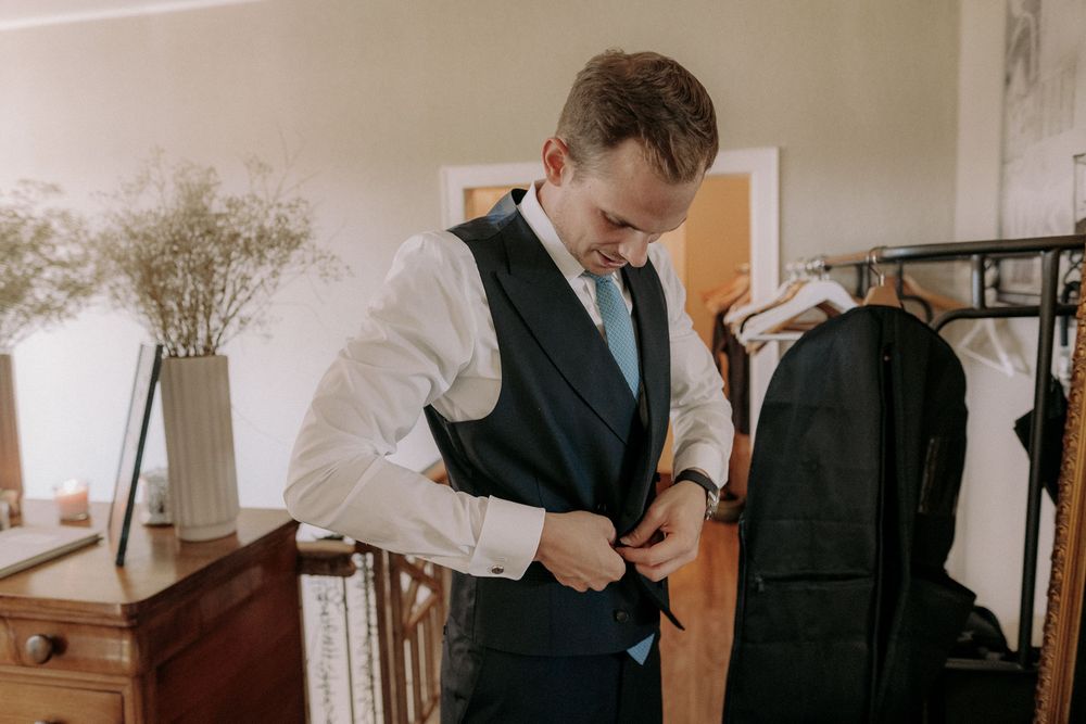 Person putting on formal vest before wedding ceremony.